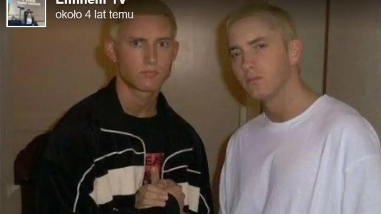 Dwóch młodych mężczyzn, jeden w czarnej bluzie, drugi w białej koszulce, pozuje do zdjęcia. Czy eminem żyje? Tak, ten artysta ma się dobrze.