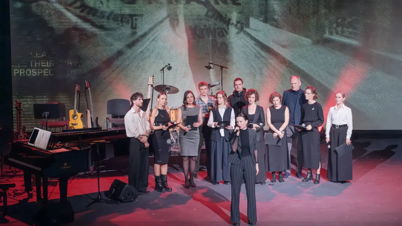 Grupa artystów na scenie, gdzie odbywa się koncert dla Ukrainy. W tle ekran z napisem "UKRAINE".