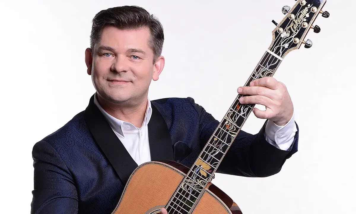 Uśmiechnięty Zenek Martyniuk z gitarą. Dowiedz się, gdzie najbliższy koncert Zenka Martyniuka i baw się świetnie!