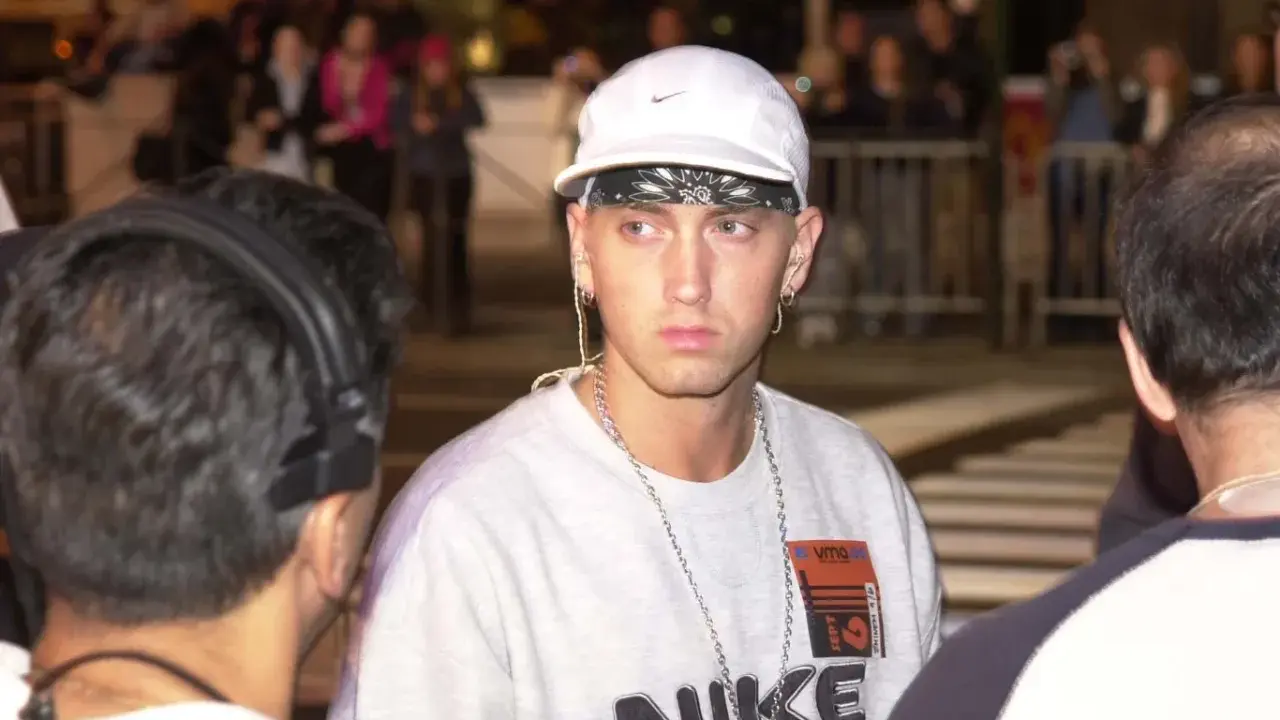 Eminem w białej czapce i z łańcuchami na szyi. Zastanawiasz się, ile Eminem ma piosenek?