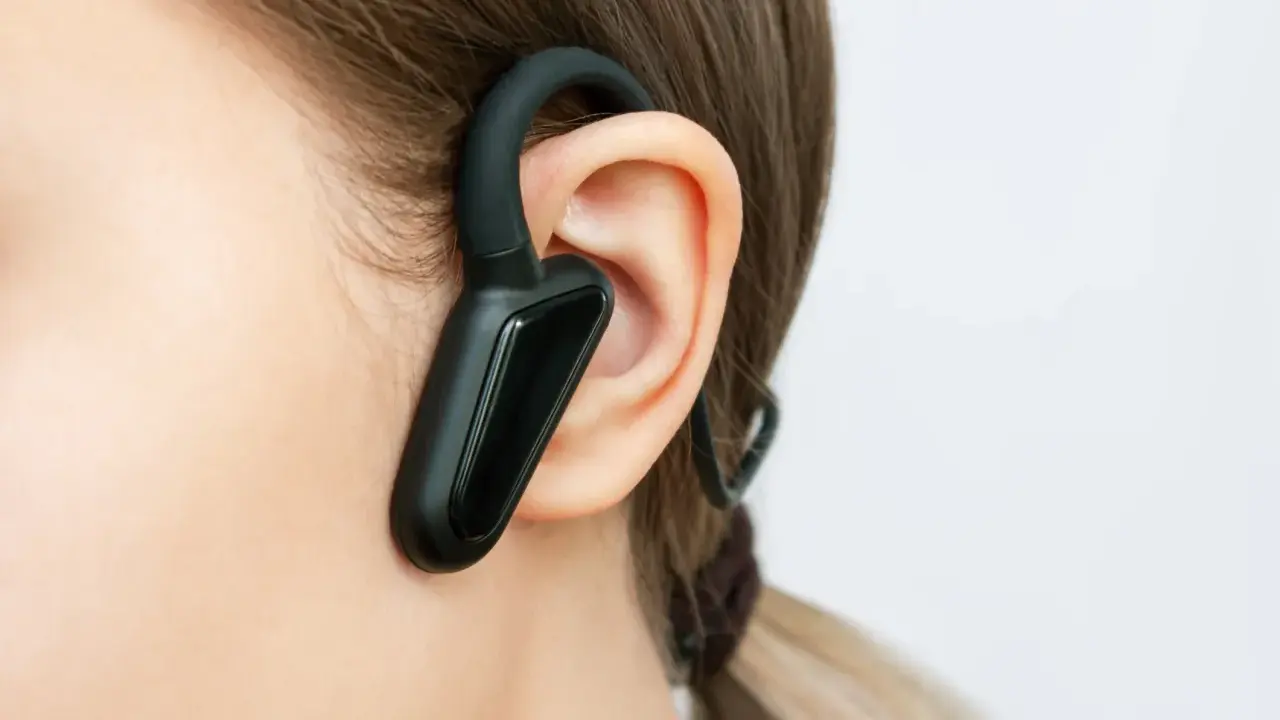 Czarna słuchawka bluetooth na uchu, idealna do rozmów w biegu.