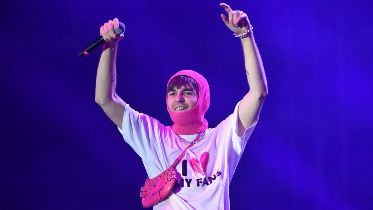 Mata z mikrofonem i różową kominiarką na głowie, w koszulce "I ❤️ MY FANS". Fani zastanawiają się, ile trwają koncerty Maty.