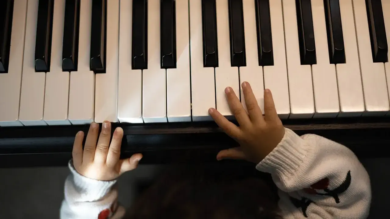 Małe rączki na klawiaturze pianina, jakby szukały melodii, która tworzy teksty piosenek które dają do myślenia.