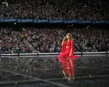 Taylor Swift w czerwonej sukni na scenie, śpiewa dla tłumu. Zastanawiasz się, ile trwa koncert Taylor Swift?