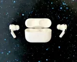 Białe słuchawki AirPods z etui na czarnym tle w gwiazdy.