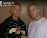 Dwóch młodych mężczyzn, jeden w czarnej bluzie, drugi w białej koszulce, pozuje do zdjęcia. Czy eminem żyje? Tak, ten artysta ma się dobrze.