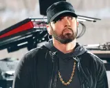 Eminem w czapce i z łańcuchem na szyi. W tle sprzęt muzyczny. Ciekawe, ile ma lat Eminem?