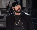 Eminem w czapce i złotej koli, z miną sugerującą zdziwienie, jakby usłyszał pytanie: czemu Eminem nie lubi Polski.