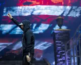 Eminem na koncercie, z palcem w górze, na tle amerykańskiej flagi. Czy Eminem nie lubi Polaków? Nie ma dowodów na to w jego twórczości.