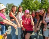 Grupa młodych kobiet z numerami na rękach, podekscytowana przed koncertem. Czekają, by dowiedzieć się, ile trwa koncert Eda Sheerana.