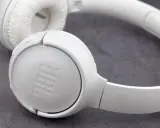 Białe słuchawki nauszne JBL na szarym tle.