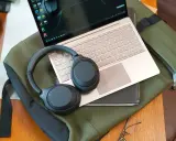 Słuchawki bezprzewodowe Sony leżą na laptopie i zielonej torbie.