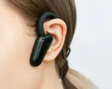 Czarna słuchawka bluetooth na uchu, idealna do rozmów w biegu.