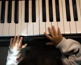 Małe rączki na klawiaturze pianina, jakby szukały melodii, która tworzy teksty piosenek które dają do myślenia.