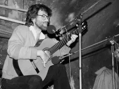 Mężczyzna w okularach gra na gitarze, śpiewając. Słychać tylko jego głos i muzykę, jak w tekście piosenki "jaki tu spokój".