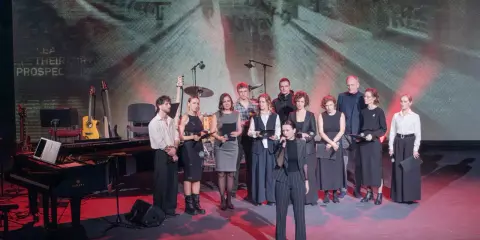 Grupa artystów na scenie, gdzie odbywa się koncert dla Ukrainy. W tle ekran z napisem "UKRAINE".