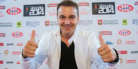 Uśmiechnięty mężczyzna w białej kurtce daje kciuki w górę. Czy to on śpiewa, a ona tańczy dla niego?