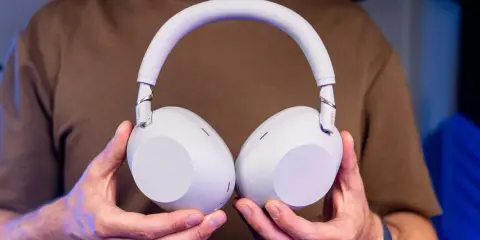Jasnoszare słuchawki Sony trzymane w dłoniach.