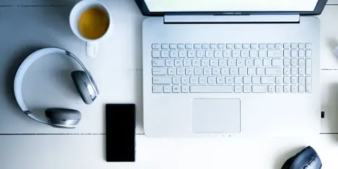 Laptop, słuchawki bezprzewodowe, telefon i kawa. Dowiedz się, jak podłączyć słuchawki bezprzewodowe do laptopa.