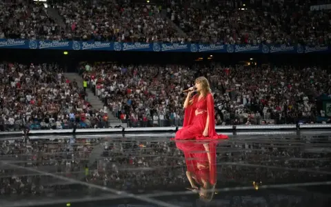 Taylor Swift w czerwonej sukni na scenie, śpiewa dla tłumu. Zastanawiasz się, ile trwa koncert Taylor Swift?