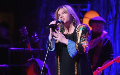 Anna Dąbrowska śpiewa na scenie. Koncert trwa, a fani zastanawiają się, ile trwa koncert Ani Dąbrowskiej.
