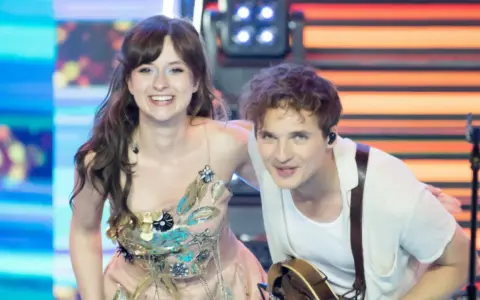 Kto śpiewa Kwiat Jabłoni? To młoda para artystów na scenie, ona w ozdobnej sukni, on z gitarą.