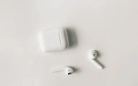 Białe słuchawki AirPods i etui na białym tle. Czy airpods działają z androidem? Tak, można je sparować.