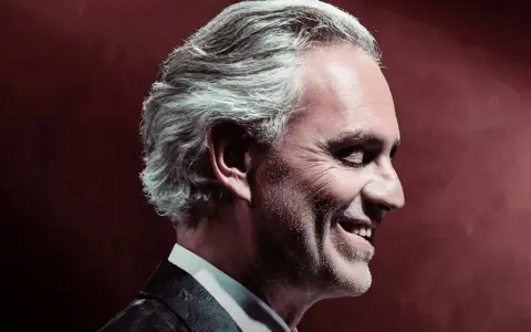 Uśmiechnięty Andrea Bocelli w garniturze. Zastanawiasz się, ile trwa koncert Andrea Bocelli?