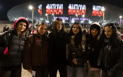 Grupa młodych kobiet czeka na koncert Maty w Krakowie. Na Tauron Arenie świeci napis #MATA2040.