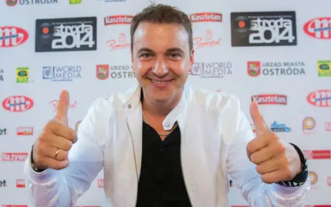 Uśmiechnięty mężczyzna w białej kurtce daje kciuki w górę. Czy to on śpiewa, a ona tańczy dla niego?