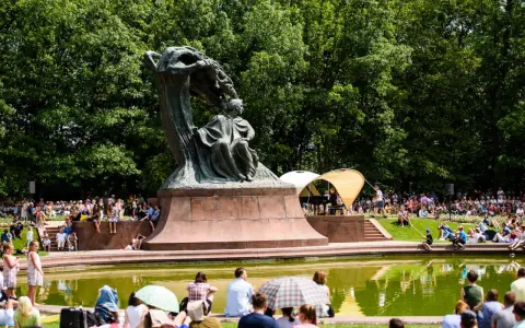 Koncert chopinowski w Łazienkach Królewskich. Tłumy słuchają muzyki przy pomniku Chopina.