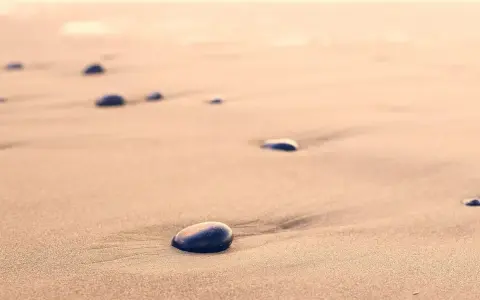Spacer dzika plaża. Kamienie na piasku, szum fal. Kto śpiewa? Może wiatr?