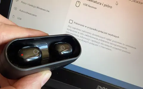 Dłoń trzyma czarne słuchawki w etui, obok ekranu laptopa z ustawieniami, pokazując jak sparować słuchawki z laptopem.