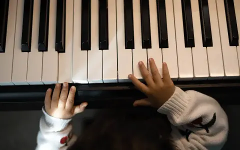 Małe rączki na klawiaturze pianina, jakby szukały melodii, która tworzy teksty piosenek które dają do myślenia.