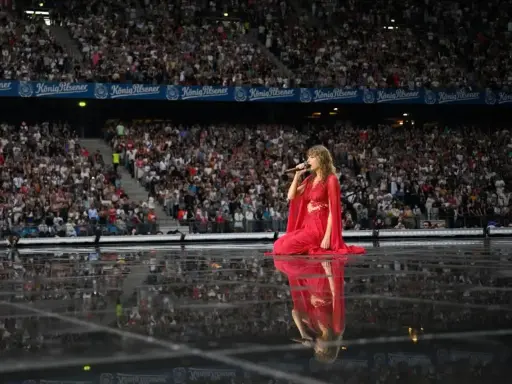 Taylor Swift w czerwonej sukni na scenie, śpiewa dla tłumu. Zastanawiasz się, ile trwa koncert Taylor Swift?