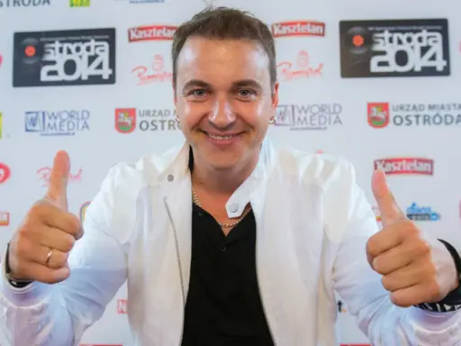 Uśmiechnięty mężczyzna w białej kurtce daje kciuki w górę. Czy to on śpiewa, a ona tańczy dla niego?