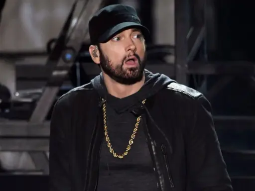 Eminem w czapce i złotej koli, z miną sugerującą zdziwienie, jakby usłyszał pytanie: czemu Eminem nie lubi Polski.