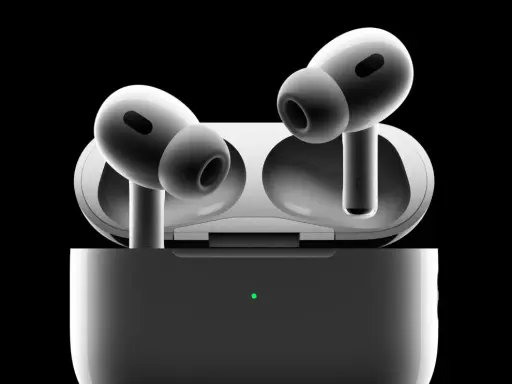 Białe słuchawki AirPods Pro w etui z zieloną diodą, na czarnym tle.