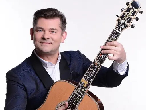 Uśmiechnięty Zenek Martyniuk z gitarą. Dowiedz się, gdzie najbliższy koncert Zenka Martyniuka i baw się świetnie!
