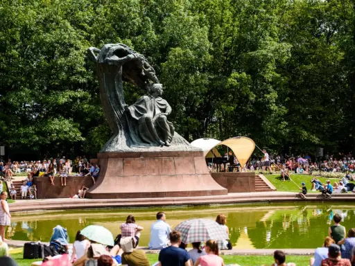 Koncert chopinowski w Łazienkach Królewskich. Tłumy słuchają muzyki przy pomniku Chopina.