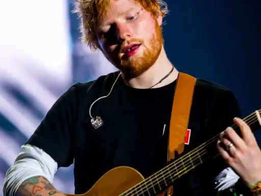 Ed Sheeran gra na gitarze, a jego wiek to 33 lata.