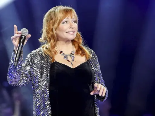 Kobieta w błyszczącej marynarce śpiewa na scenie. Czy to ona na alei gwiazd, kto śpiewa?