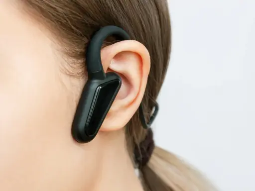 Czarna słuchawka bluetooth na uchu, idealna do rozmów w biegu.