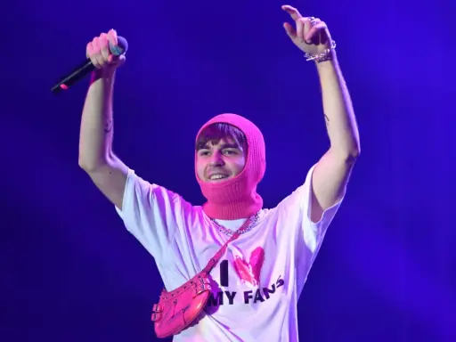 Mata z mikrofonem i różową kominiarką na głowie, w koszulce "I ❤️ MY FANS". Fani zastanawiają się, ile trwają koncerty Maty.