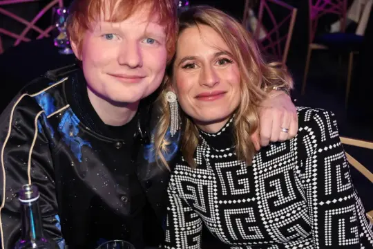 Ed Sheeran z żoną Cherry Seaborn, uśmiechnięci, w eleganckich strojach.