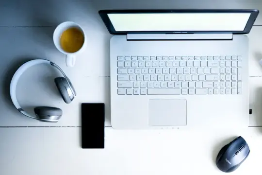 Laptop, słuchawki bezprzewodowe, telefon i kawa. Dowiedz się, jak podłączyć słuchawki bezprzewodowe do laptopa.
