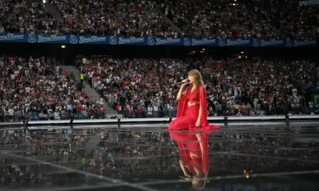 Taylor Swift w czerwonej sukni na scenie, śpiewa dla tłumu. Zastanawiasz się, ile trwa koncert Taylor Swift?