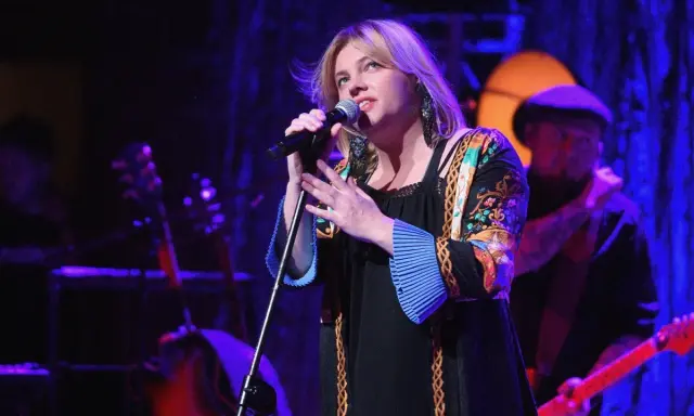 Anna Dąbrowska śpiewa na scenie. Koncert trwa, a fani zastanawiają się, ile trwa koncert Ani Dąbrowskiej.