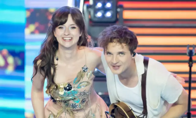 Kto śpiewa Kwiat Jabłoni? To młoda para artystów na scenie, ona w ozdobnej sukni, on z gitarą.