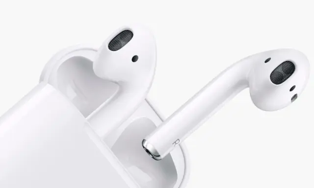 Białe słuchawki AirPods w etui. Dowiedz się, jak sprawdzić ile AirPods mają baterii, by zawsze cieszyć się muzyką.